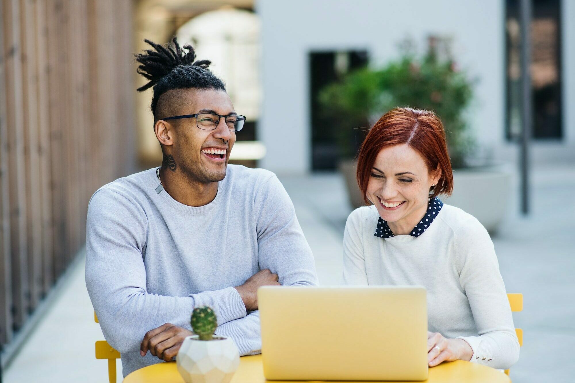 Young businesspeople with laptop in courtyard, start-up concept